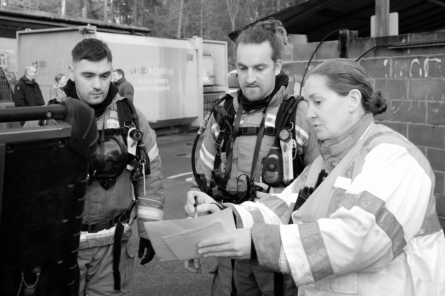 Black and white image of two firefighters being briefed by the incident commander.