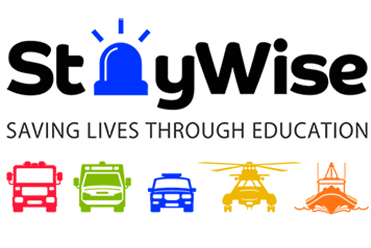 Staywise logo with the tag line "Saving Lives Through Education" followed by a graphic of a red fire engine, green ambulance, blue police car, yellow helicopter and orange boat.