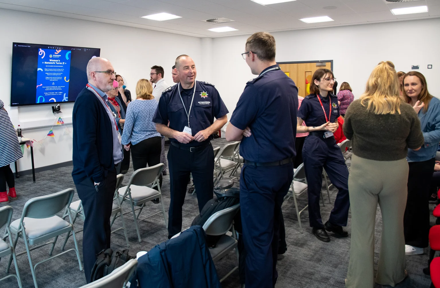 a group of people stand around a room talking