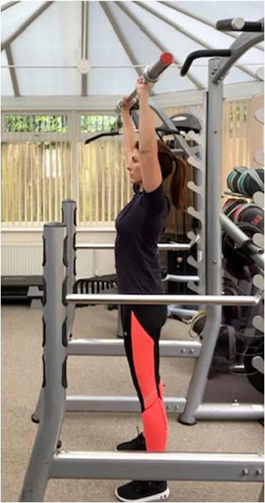 Overhead press viewed from the side with bar full extended above the head