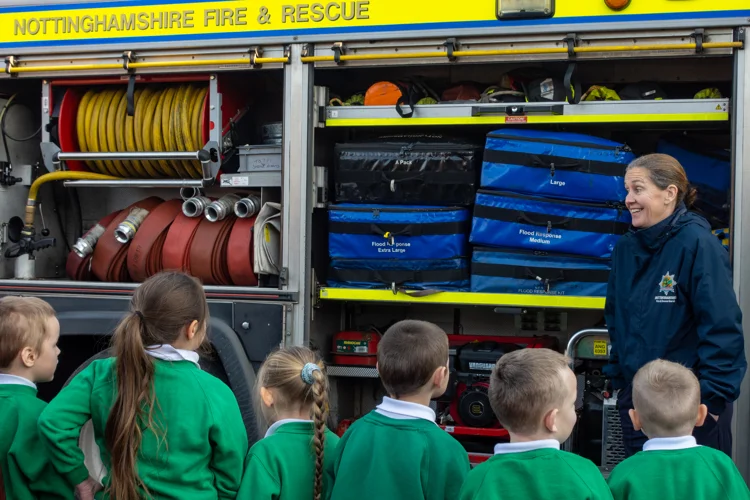 Schoolchildren lined up listening to a firefighter explain about her role.