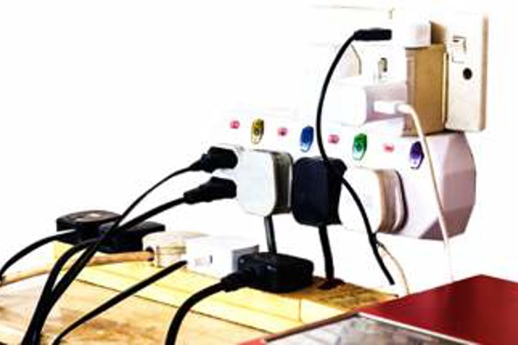 An overloaded electrical socket with lots of devices all plugged into the same extension