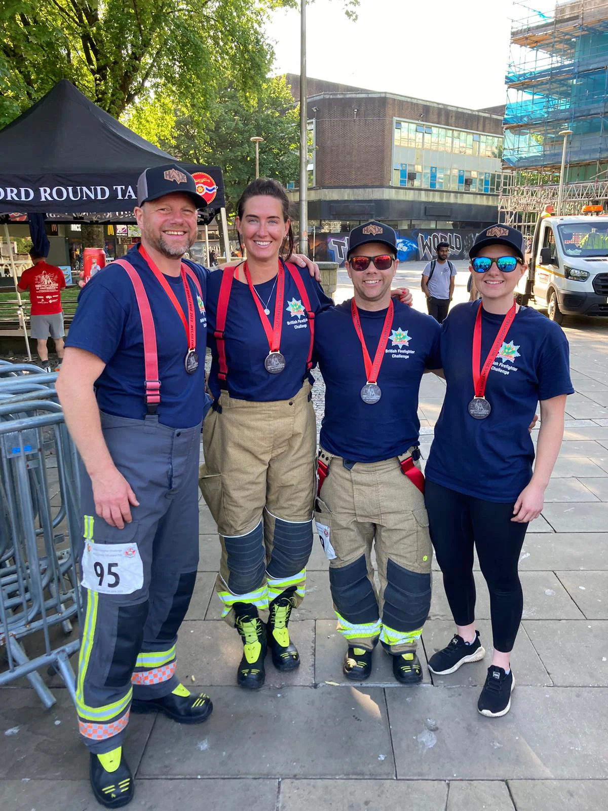 a group of four firefighters stand in a line, all wearing medals