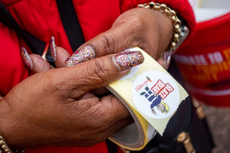 hands hold a reel of sticker that read the fire fighter's charity. on the sticker is also a picture of blaze bear.