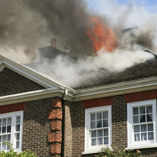 A house on fire with smoke and flames seen coming from the roof