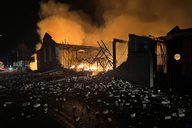 Rubble on the road and building on fire behind.