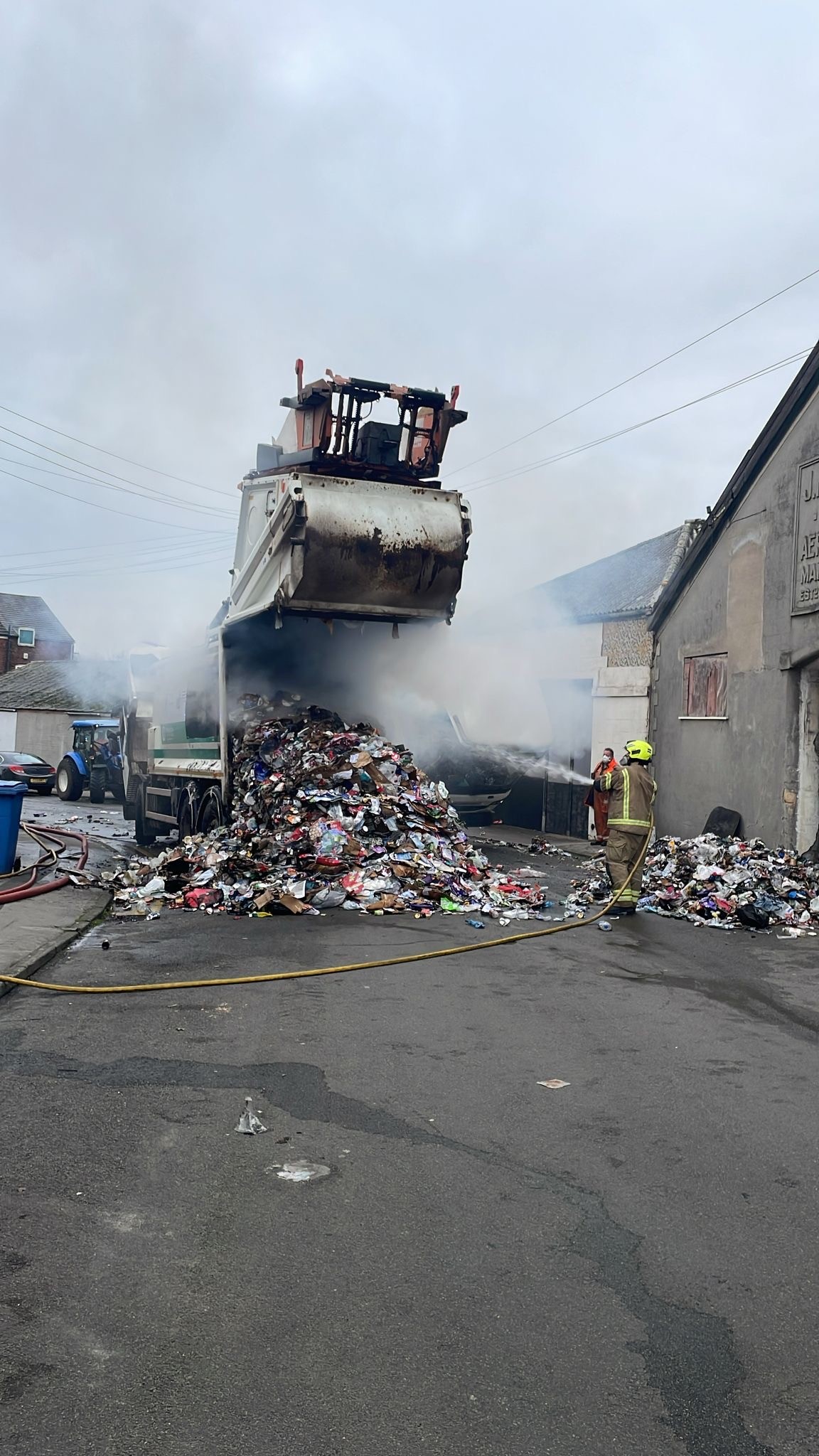 Waste on the floor coming out of a lorry whilst firefighters tackle the fire