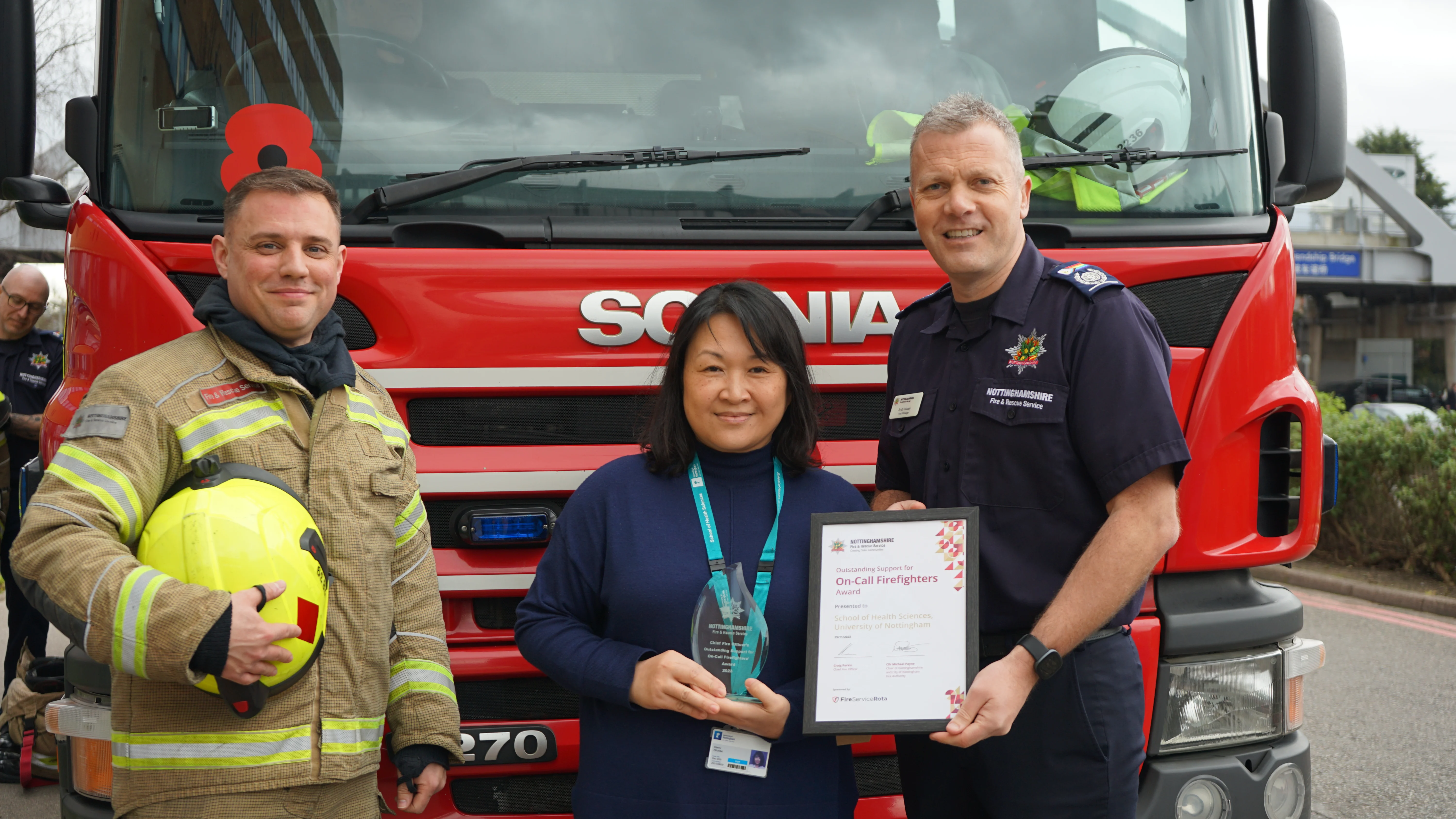 Aaron, Cherry and Andy smile in front of the fire engine as the award is presented.