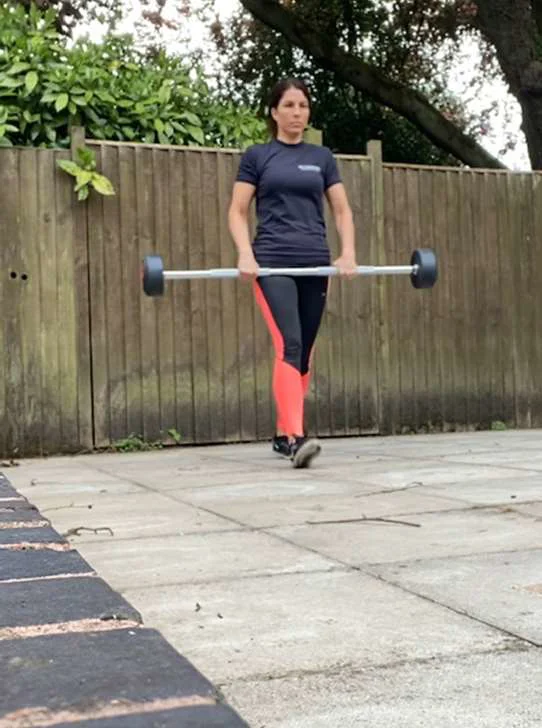 A women walking with a barbell at waist height