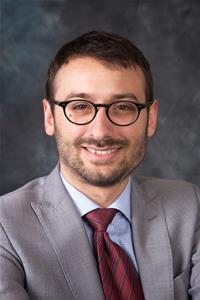 Councillor Pavlos Kotsonis wearing glasses, a gray suit and maroon tie.