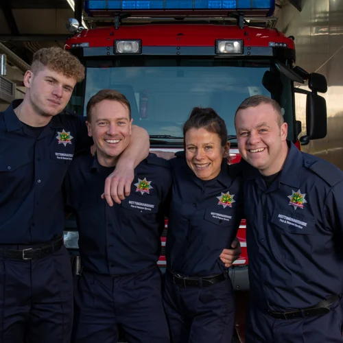 A group of four firefighters infront of a fire engine.