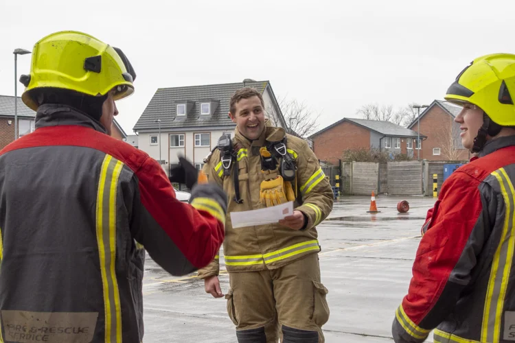 A firefighter chats with the soldiers laughing before the fitness tests