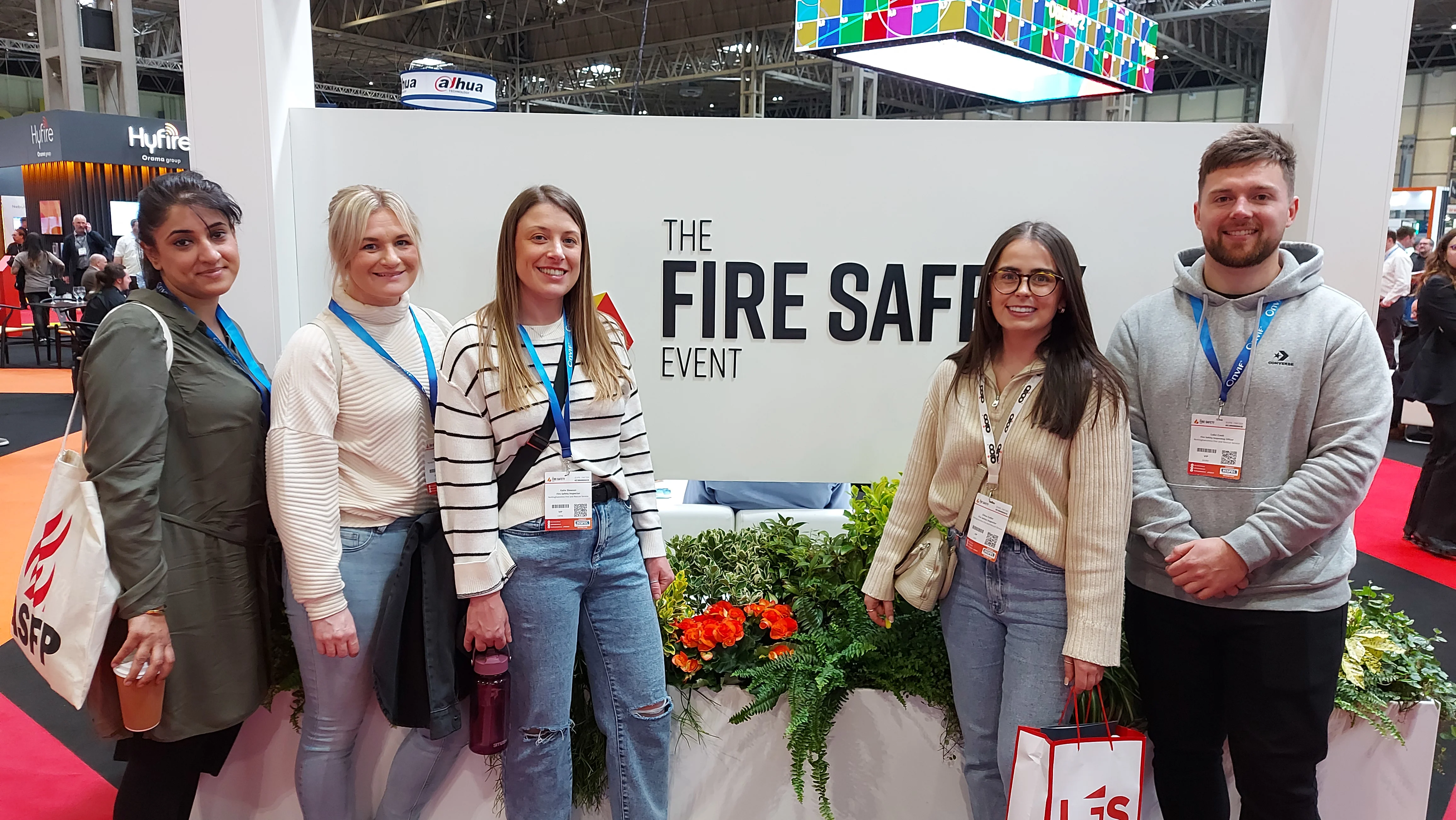 five members of the fire protection team stand in front of a sign reading 'the fire safety event'
