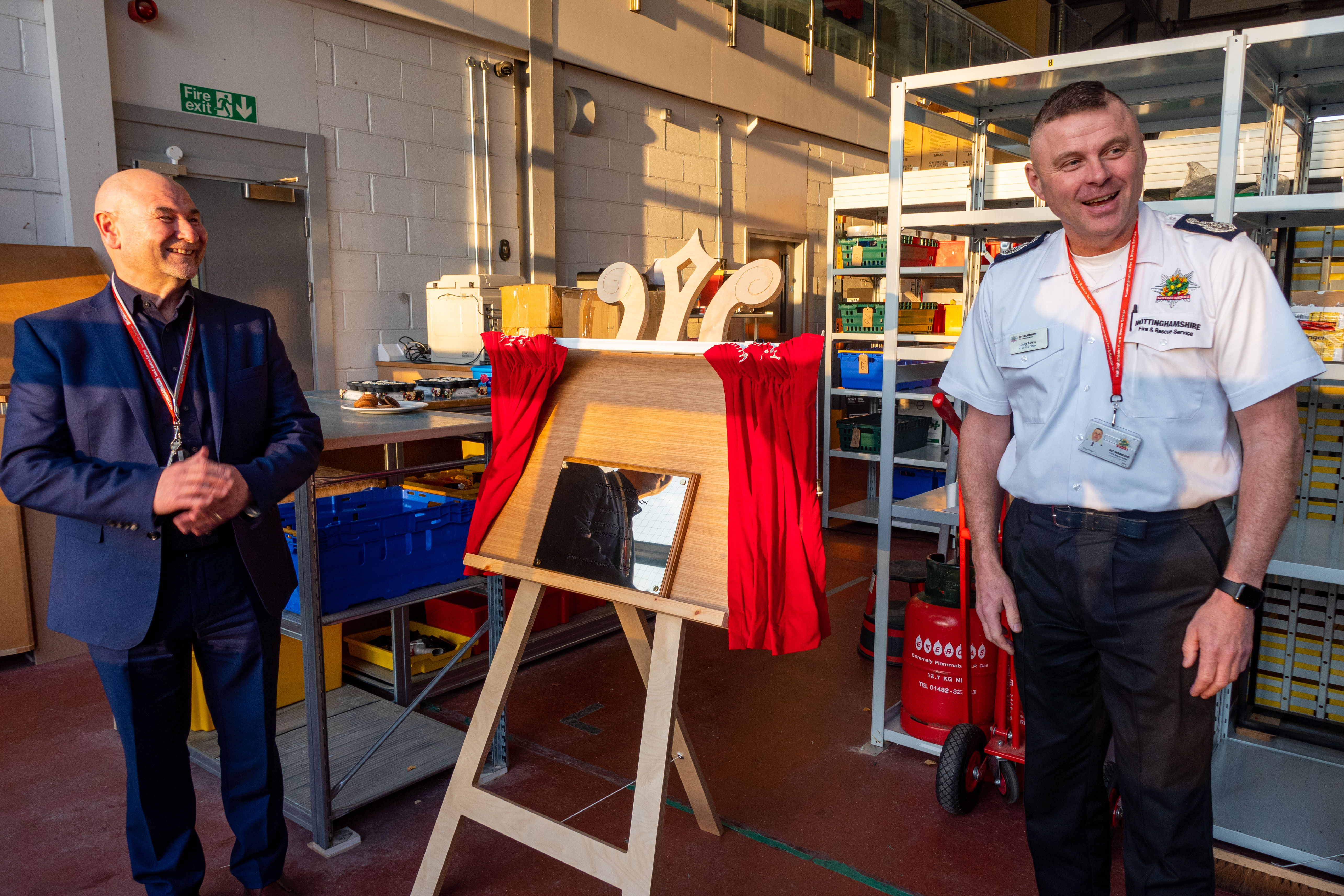 Craig Parkin laugh next to a plaque which commemorates the opening of Stores at Highfields