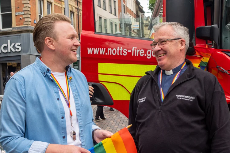 Michael Payne and Chaplain David Milner smile in front of a fire engine at Nottinghamshire Pride.