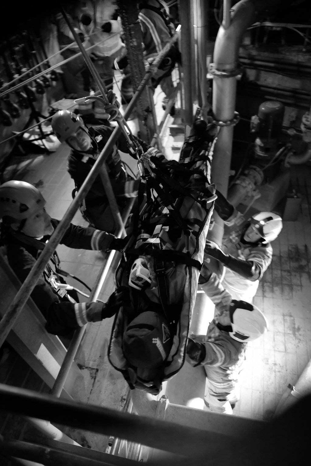 Black and white image of firefighters using rope rescue equipment to save a dummy casualty.