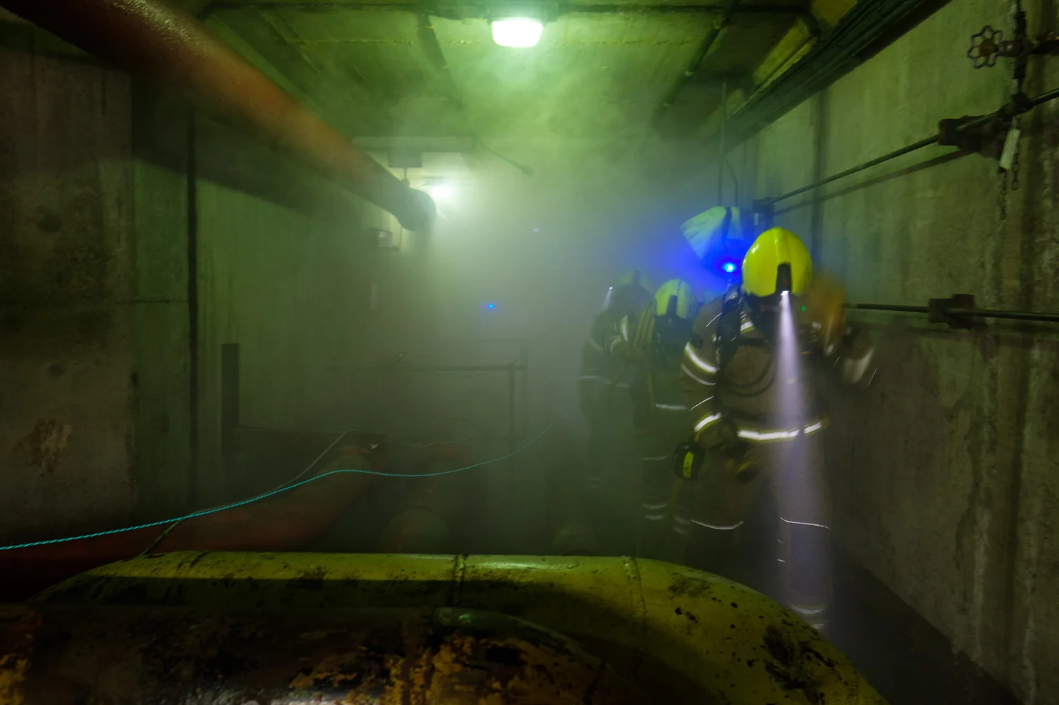 Three firefighters in an underground tunnel filled with smoke