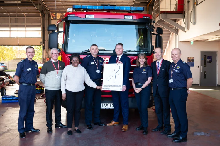Fire Authority members, the Chief Fire Officer and Chair, stand with the signed White Ribbon poster