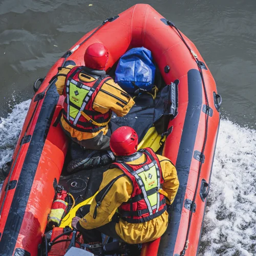 Two firefighters in water rescue kit in the rescue speed boat.