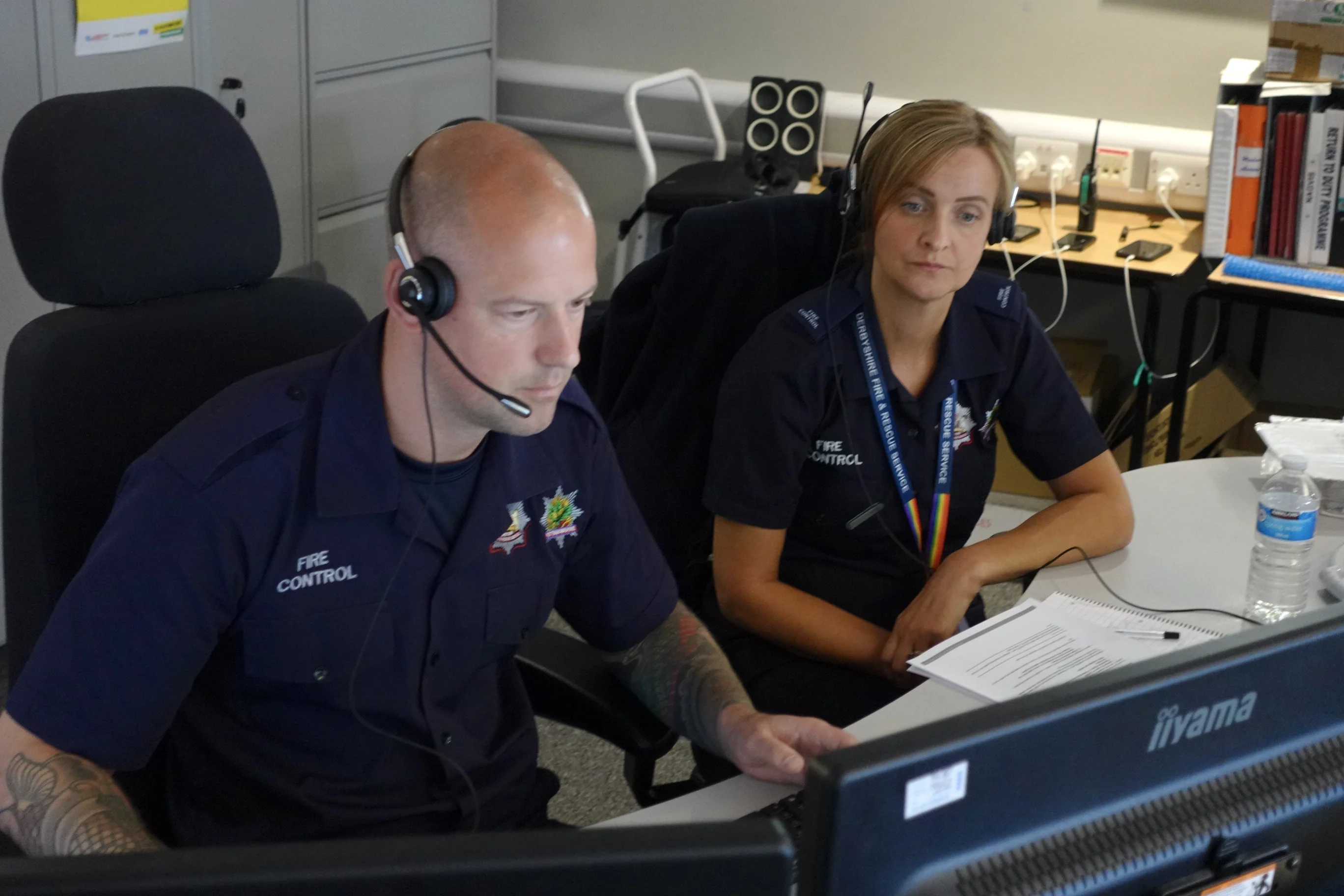 Two 999 control operators with headsets on take a 999 call