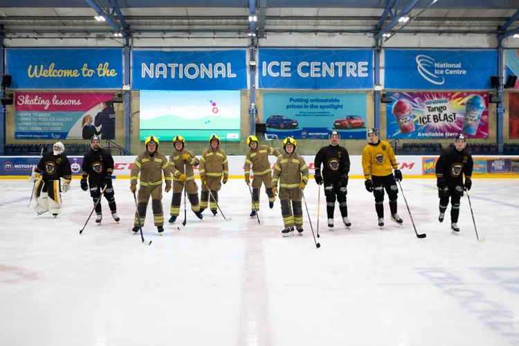 Ice hockey players and firefighters on the ice skating towards us