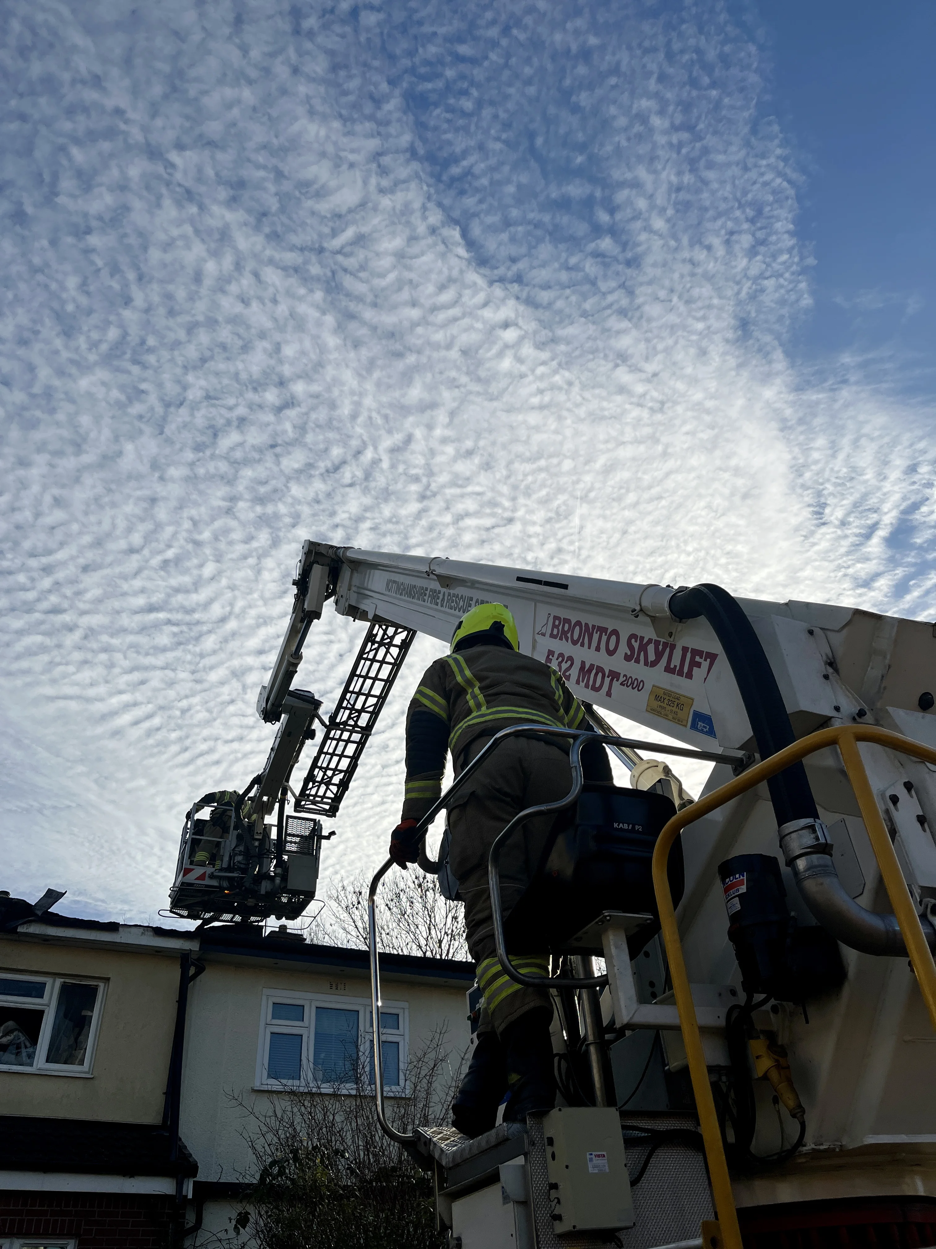 the aerial ladder platform takes roof tiles off a house that has been damaged by fire