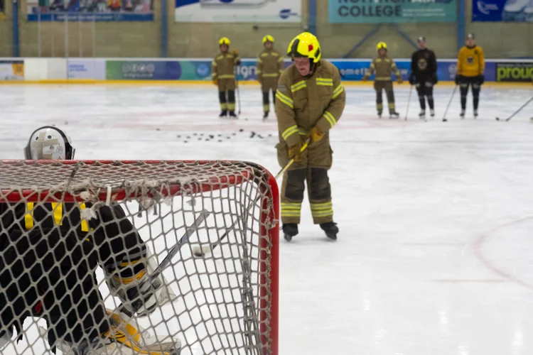 Firefighter on the ice in fire kit attempting to score 