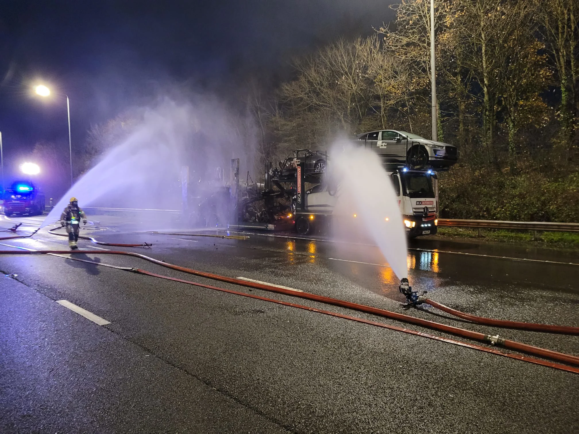 transportation HGV with two hoses pointing at it. cars burnt out