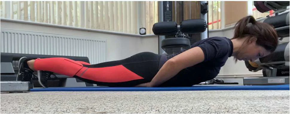 A women demonstrating a back extension whilst lying face down on the floor
