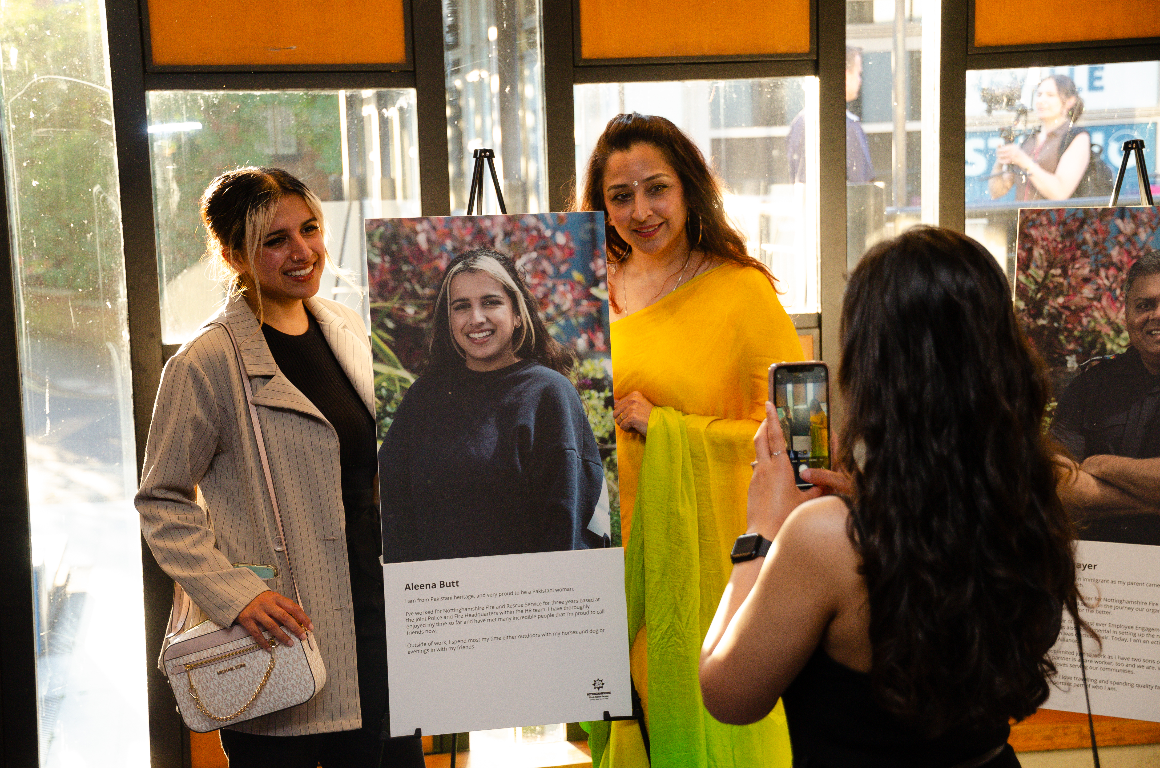 Two members of staff standing next to a portrait having their photo taken