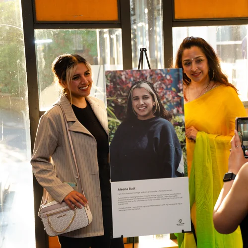 Two members of staff standing next to a portrait having their photo taken