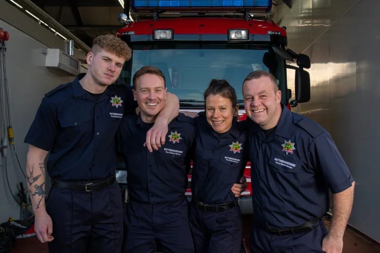 Four firefighters with their arms around each others shoulders