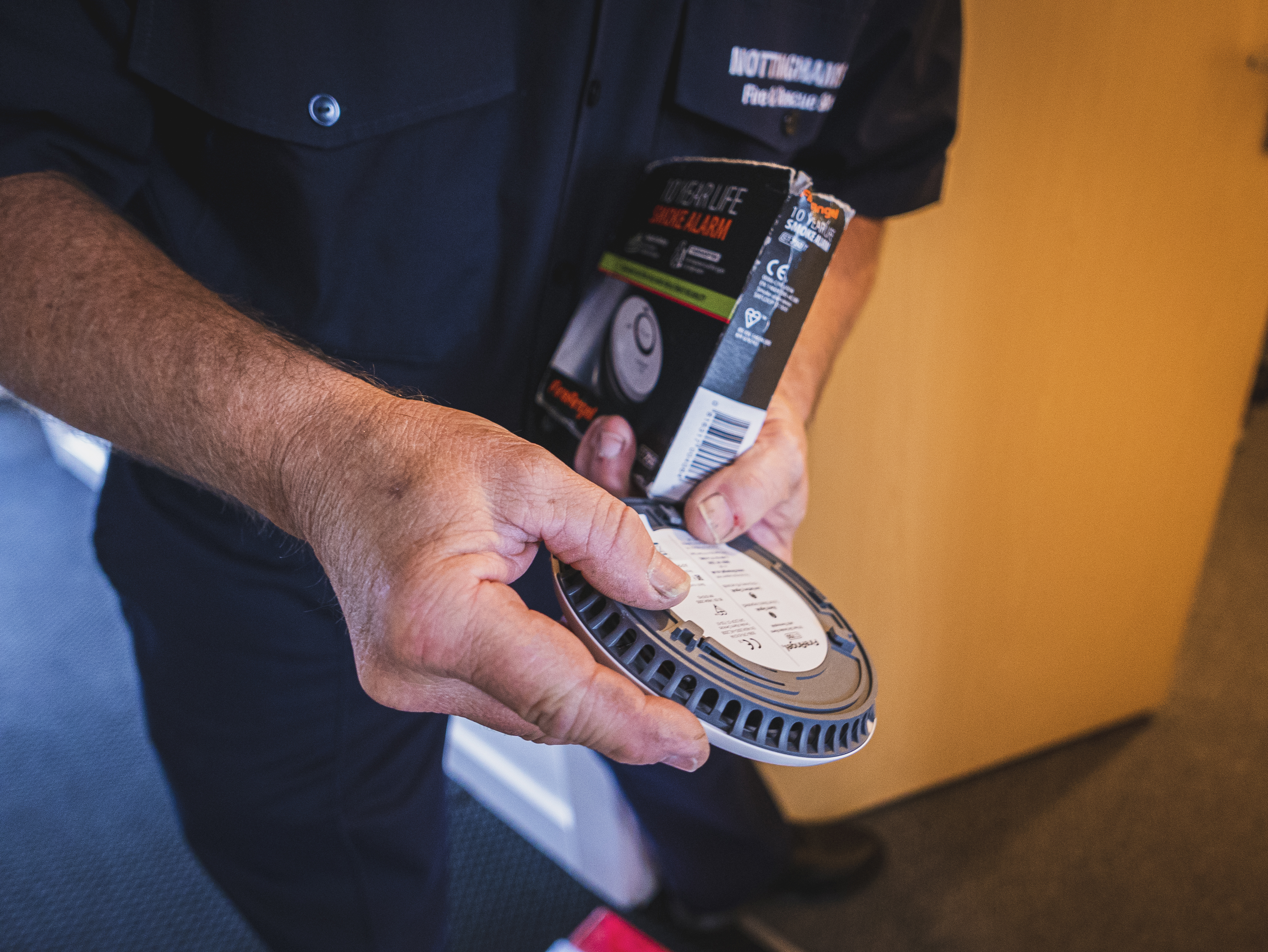 Close-up of a firefighter holding a smoke alarm and the box it came in.
