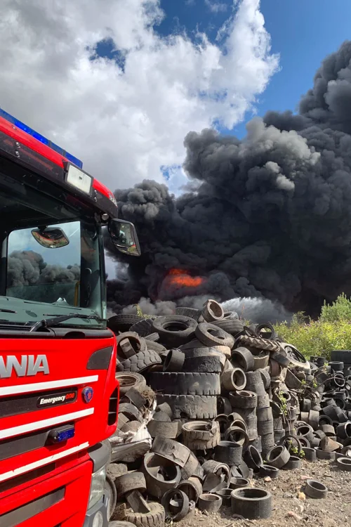 A fire engine with tyres and a large black smoke plume behind it