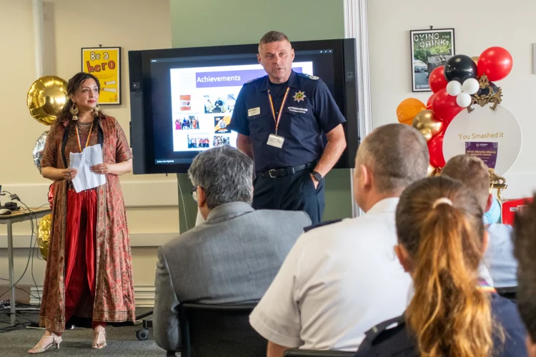 The Chief Fire Officer and Guninder Nagi stand at the front speaking to the crowd