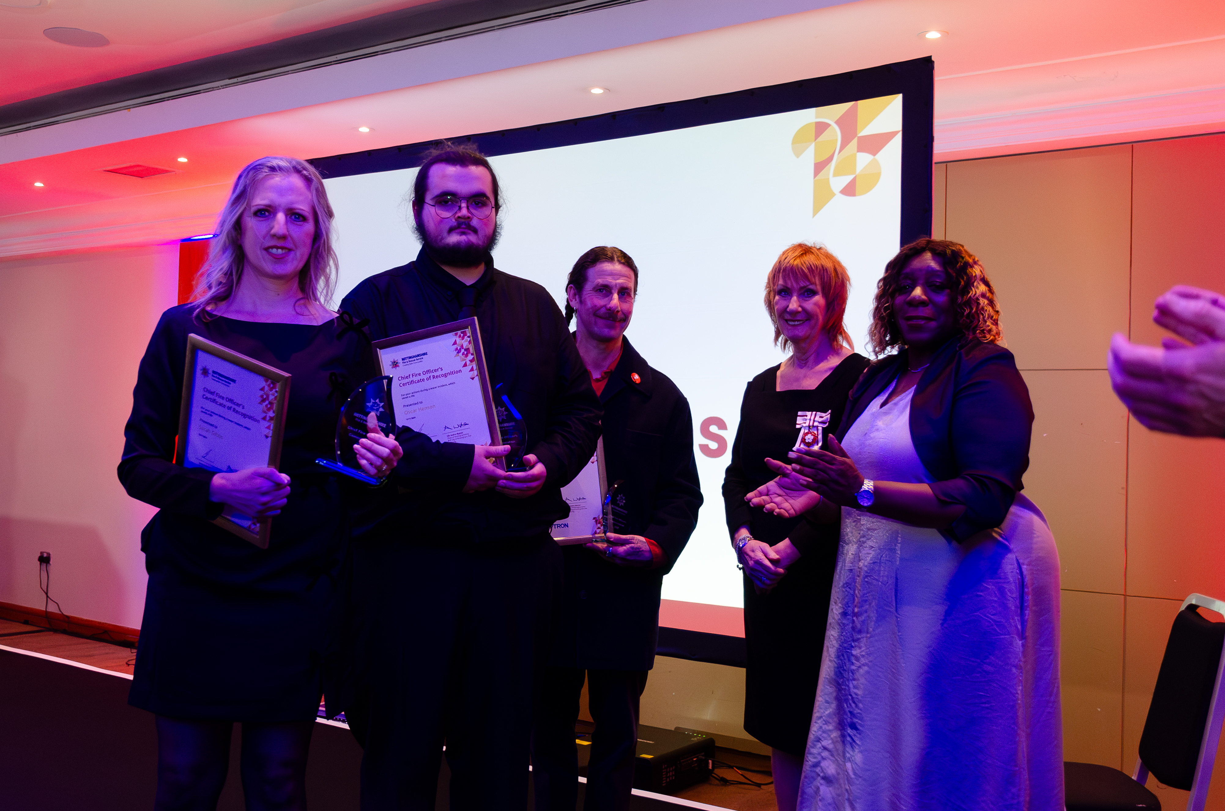 three award winners on stage collecting their award