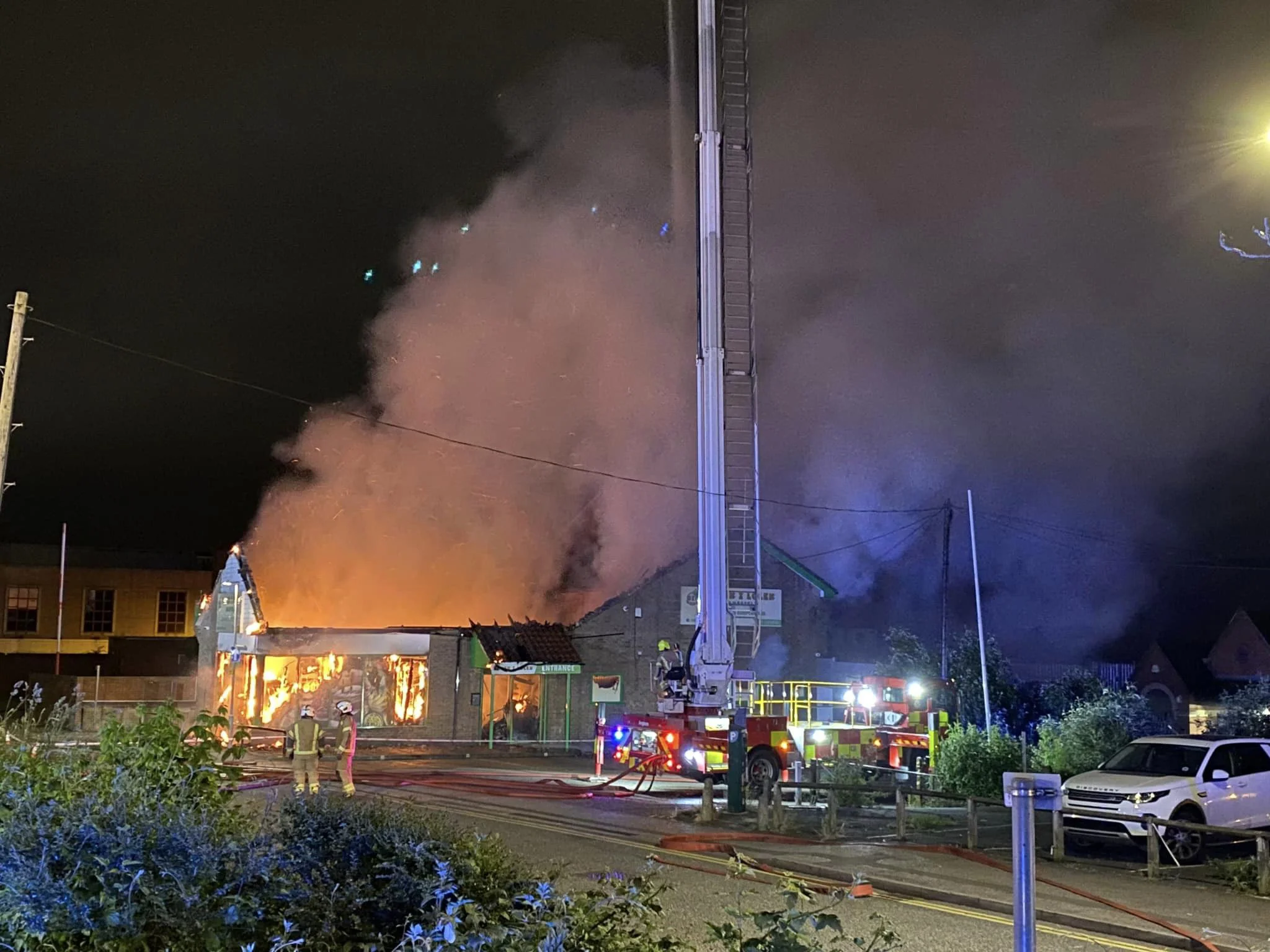 building on fire with firefighters and the aerial ladder platform