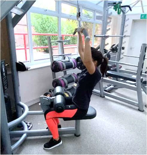 Demonstration of a lat pull down with arms full extended above the head