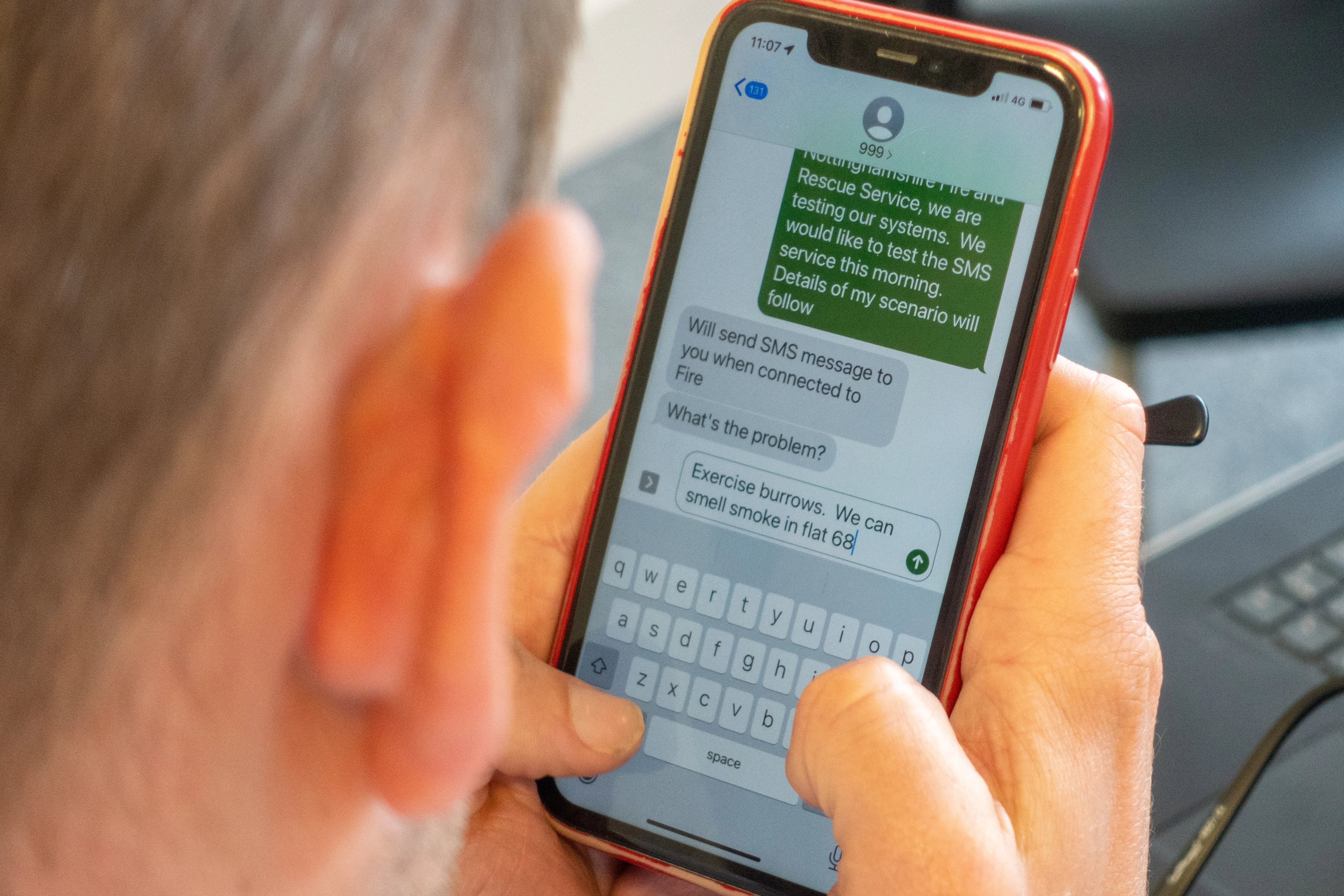 A man types in a message by text to 999 to alert them to a fire in a training scenario
