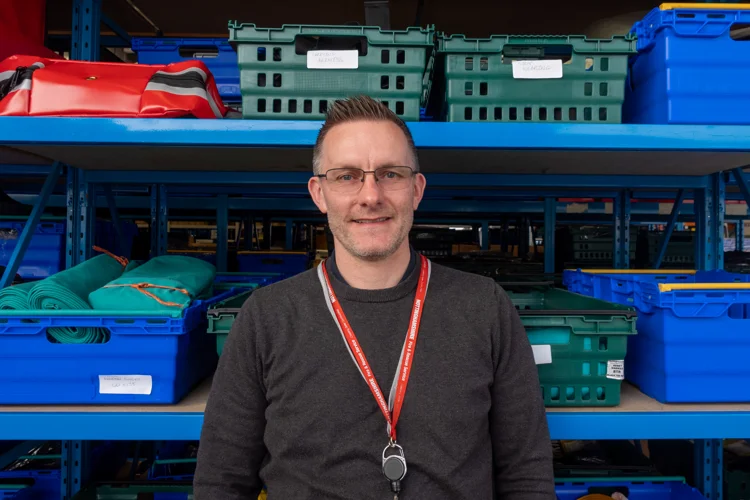 Richard smiles with Stores boxes and racking in the background.