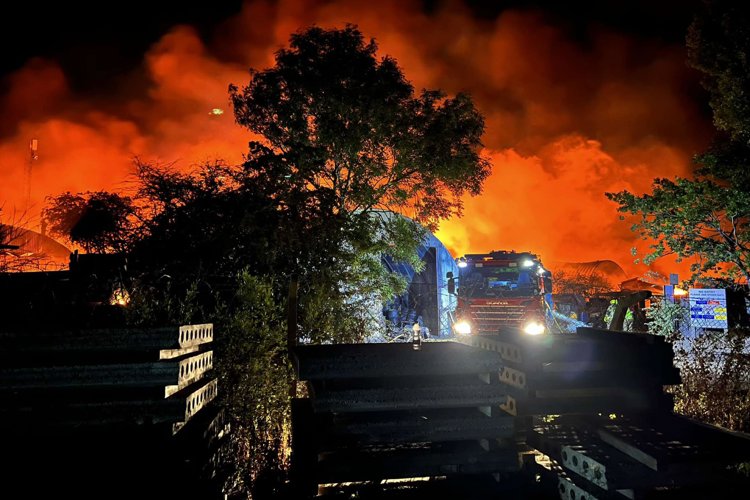 Fire engine at night with large fire in the background